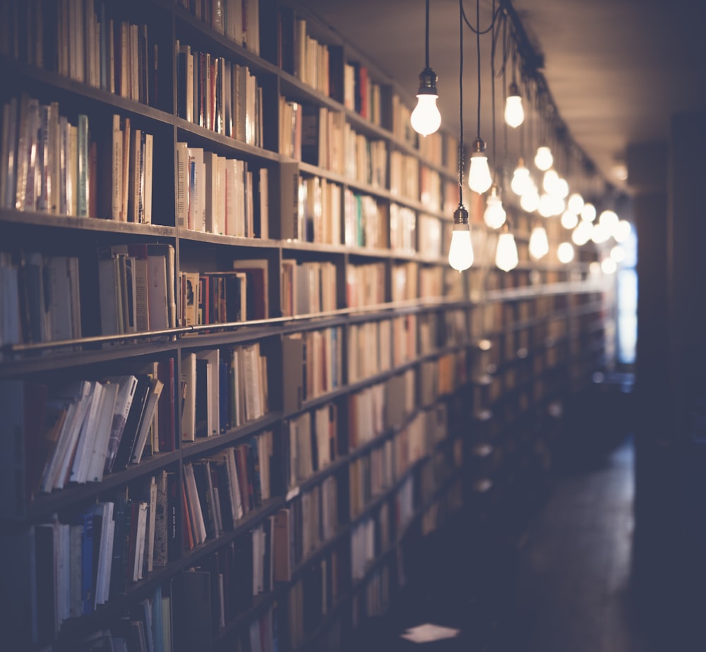A library aisle lined with books under warm lights